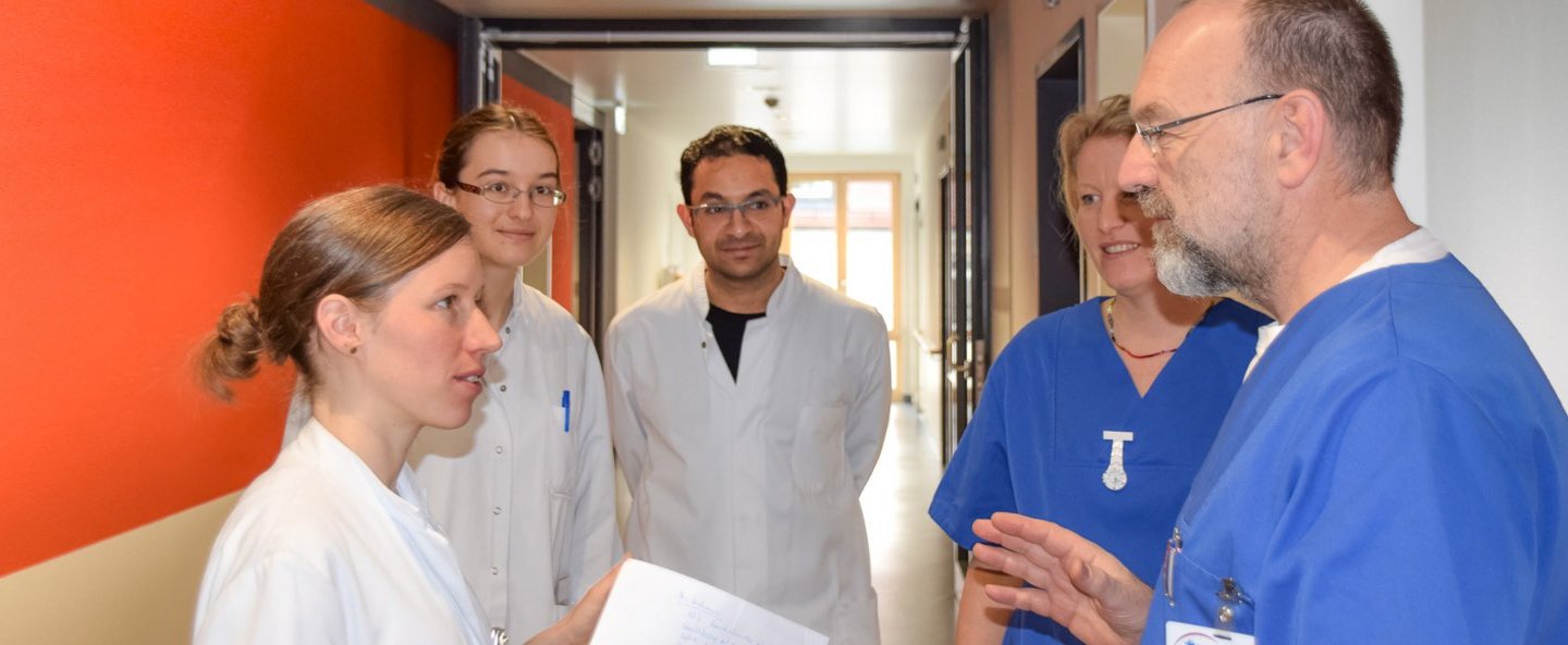 Drei Ärztinnen und Ärzte im Gespräch mit zwei Pflegefachkräften.