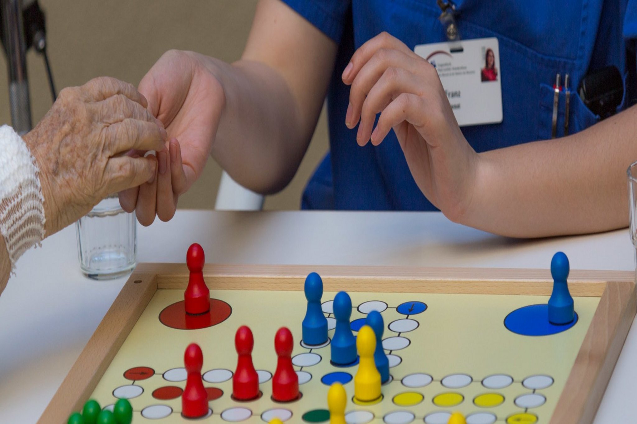 Pflegefachfrau und Patientin spielen das Brettspiel "Mensch ärgere dich nicht".